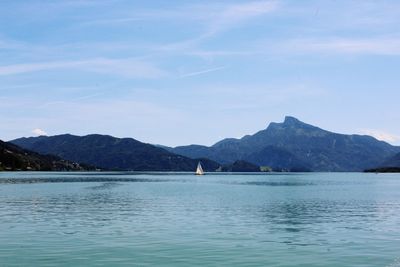 Scenic view of sea and mountains against blue sky