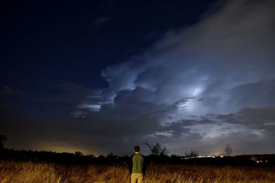 Rear view of man photographing on field at night