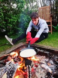 Young man with meat on barbecue grill