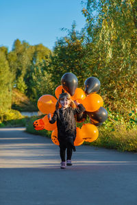 Rear view of woman with balloons on road