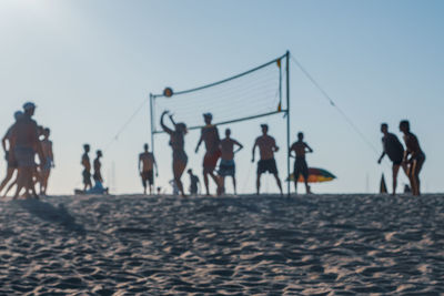 People playing on beach against clear sky