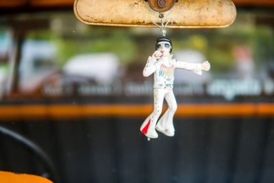 Close-up of elvis figure hanging on mirror of old car