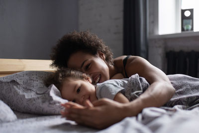 Mother and baby lying on bed at home