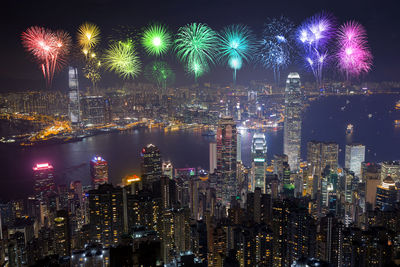 Firework display in city against sky at night