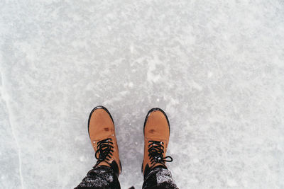 Low section of man standing on snow covered field