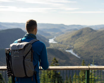 Rear view of man looking at mountains against sky