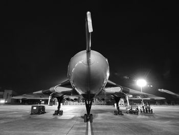 Airplane on airport runway against sky at night