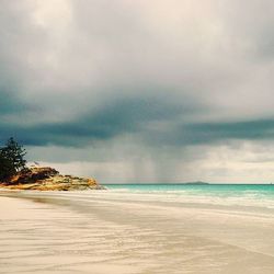 Scenic view of beach against cloudy sky