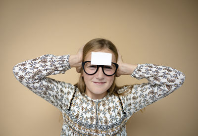 Portrait of young woman wearing sunglasses against wall