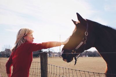 Woman standing by horse against sky