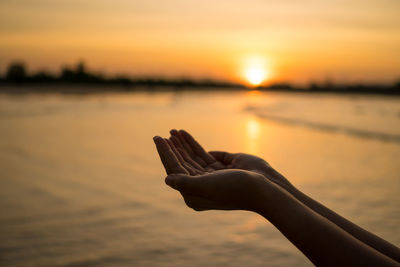 Midsection of person against sea during sunset