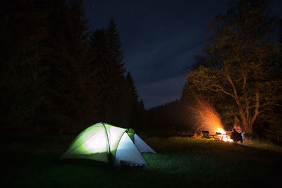 Illuminated tent on landscape against sky at night