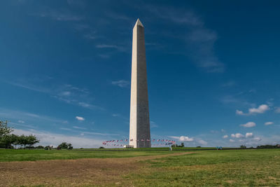 Low angle view of tower on field against cloudy sky