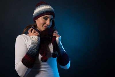 Portrait of smiling young woman against black background