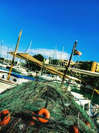 Fishing boats moored at harbor against clear blue sky