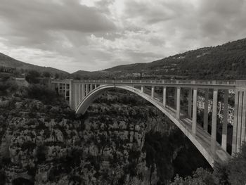 Arch bridge over mountains against sky