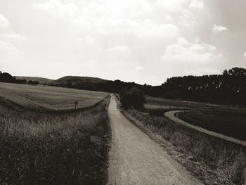 Road amidst agricultural field against sky