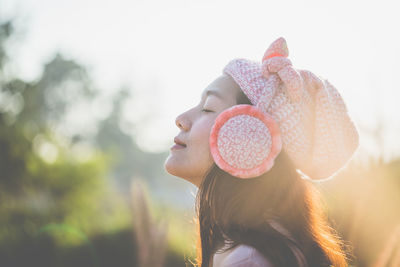 Side view of woman wearing hat and ear muffs during sunny day