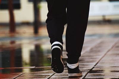 Low section of person walking on wet footpath