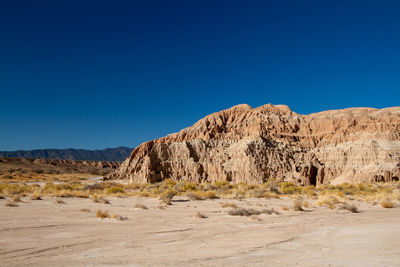 Scenic view of arid landscape against clear blue sky