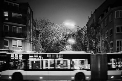 Illuminated street amidst buildings in city at night
