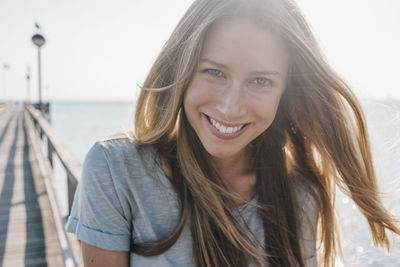 Portrait of happy young woman on jetty at backlight