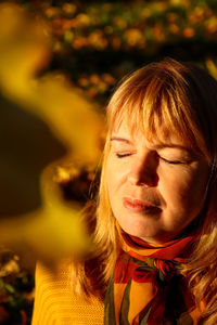 Closeup portrait of young caucasian blonde woman in colorful autumn park. bright stylish woman