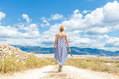 Rear view of woman standing on road against sky