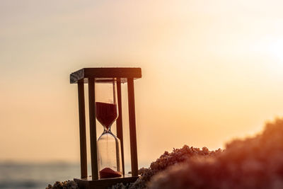 Time concept hourglass on sandy beach in summer with sea background.