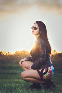 Woman standing on field against sky during sunset