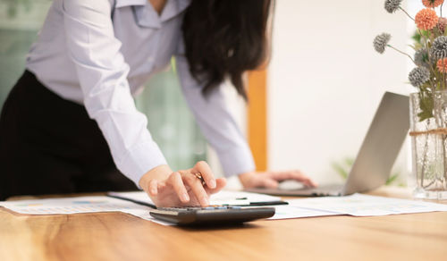 Midsection of woman using mobile phone at table