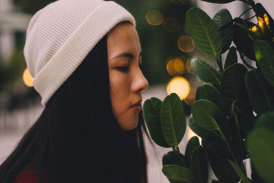 Close-up of young woman standing by leaves during sunset