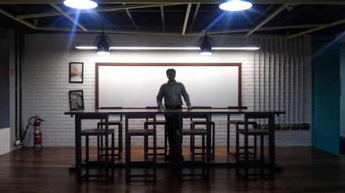 Rear view of man standing in illuminated room