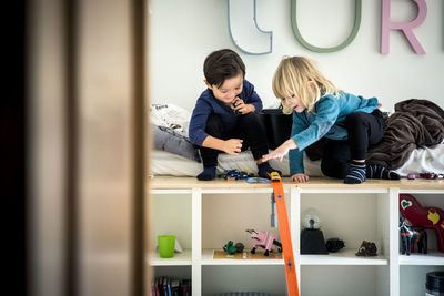 Boy and girl playing together in bedroom