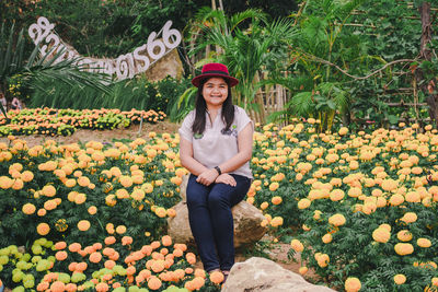 Portrait of smiling young woman standing by flowering plants