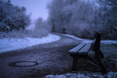 Empty bench in park during winter