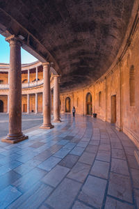 Tourist walking near pillars in patio of palace of charles v during visiting alhambra fortress complex in granada, spain