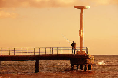 Man in sea against sky during sunset