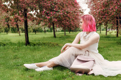 Young girl with pink hair in apple orchard.