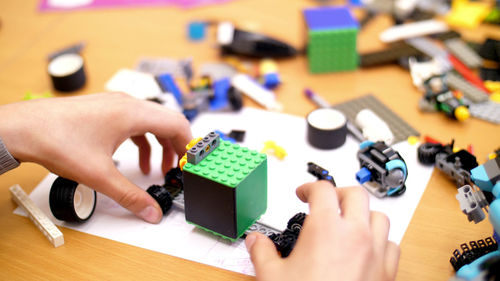 Close-up, children's hands hold a multicolored small robot, machine, assembled from a designer. 