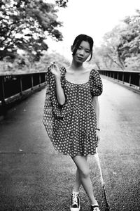 Portrait of smiling young woman standing on bridge