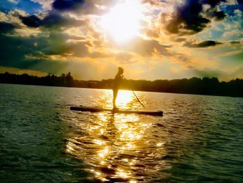 Silhouette man on shore against sky during sunset