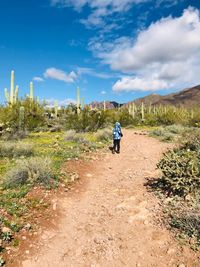 Rear view of man on dirt road against sky