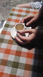 Close-up of woman holding coffee cup on table