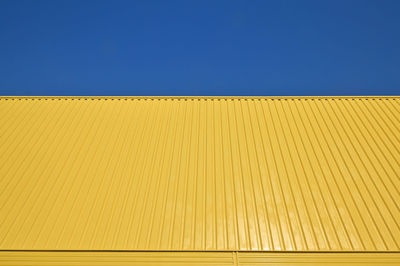 Low angle view of blue wall against clear sky