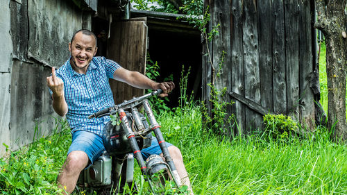 Portrait of young man with abandoned motorcycle on grassy field