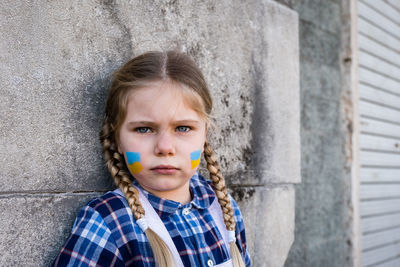 Portrait of cute girl with face paint by wall