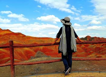 Rear view of woman standing by railing against sky