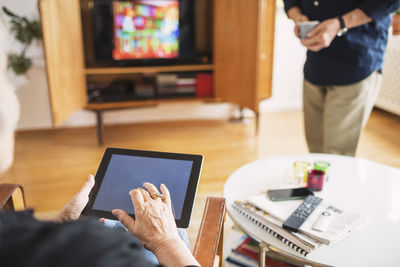 Cropped image of senior woman using tablet computer at home