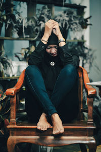 Young woman sitting on chair at home